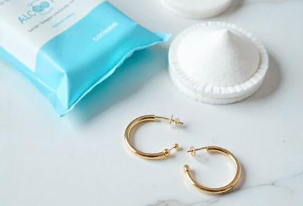 Earring cleaning tools including alcohol wipes and cotton pads used to prevent ear irritation.